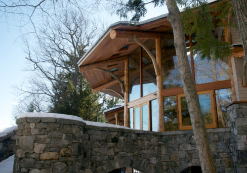 cedar log home with stone wall by Josh Belisle
